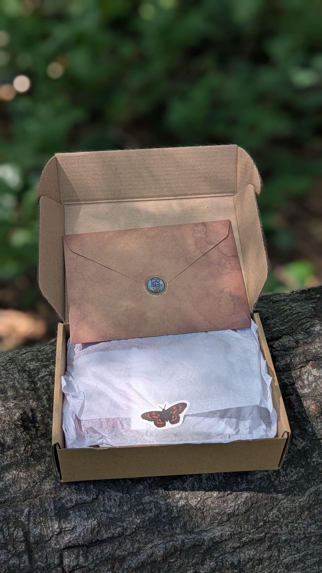 Opened box holding a wax-sealed envelope and tissue-wrapped contents